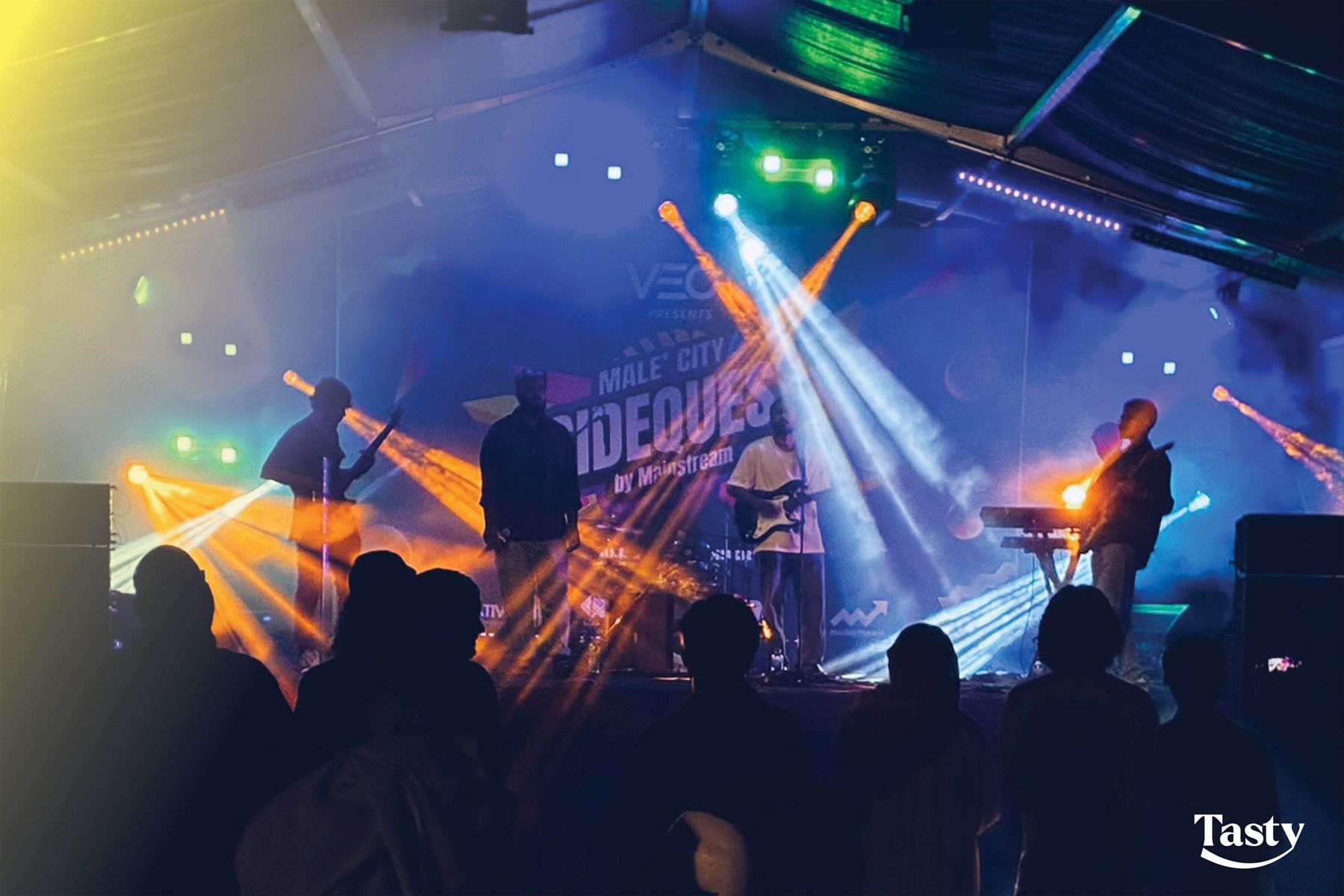 A band silhouetted under stage beams at SideQuest